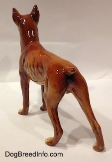 The back left side of a 1970s Boxer dog figurine. The figurine has a short tail.