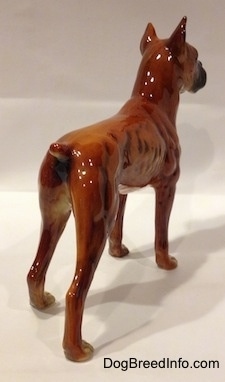 The back right side of a brown with black and white Boxer dog figurine. The figurine has fine leg details.