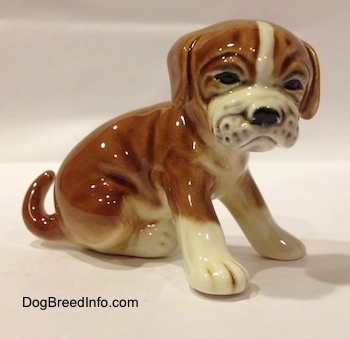 The right side of a brown with white Boxer puppy figurine. The figurine has a very detailed wrinkly face.