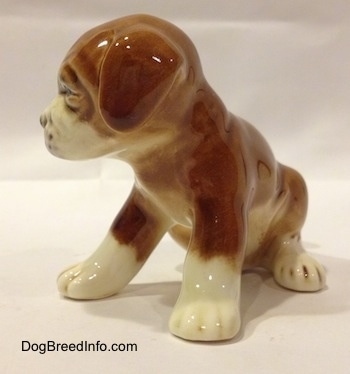 The front left side of a brown with white Boxer puppy figurine. The figurine has fine paw details.