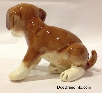 The left side of a brown with white Boxer puppy figurine. The tail of the figurine is arched up and touching the ground.