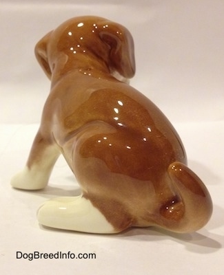 The back left side of a brown with white Boxer puppy figurine. The figurine has white paws.