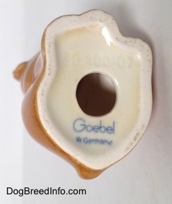 The underside of a brown Boxer puppy figurine. The figurine has a hole on its underside and the words - Goebel W.Germany - are on the bottom.