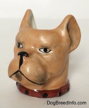 The front left side of a Stein Cup of a Boxer dogs head. The cup has a red with black collar on.