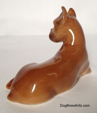 The back right of a brown with tan Boxer dog figurine in a laying down pose. The figurine has a tiny tail and it is hard to tell the difference between its body.