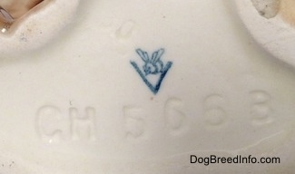 Close up - The underside of a brown with tan Boxer dog figurine in a laying down pose. There is a Goebel W. Germany stamp logo on the underside and under the logo is the numbers - CH566B.