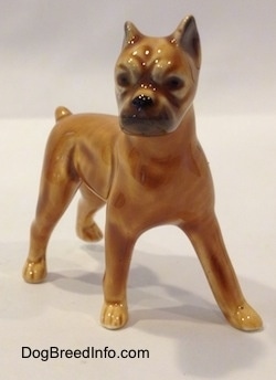 The front left side of a brown with black mini Boxer dog porcelain figurine. The figurine has black circles for eyes.