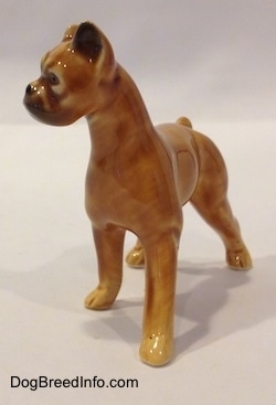 The front right side of a brown with black mini Boxer dog porcelain figurine. The figurine does not have fine paw details.
