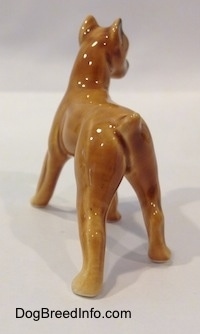 The back left side of a brown with black mini Boxer dog porcelain figurine. The figurine is very glossy.