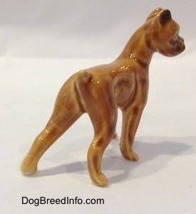 The back right side of a brown with black mini Boxer dog porcelain figurine.