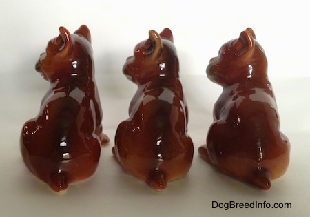 The back side of three brown with white and black Boxer puppy figurines. All the figurines are very glossy.