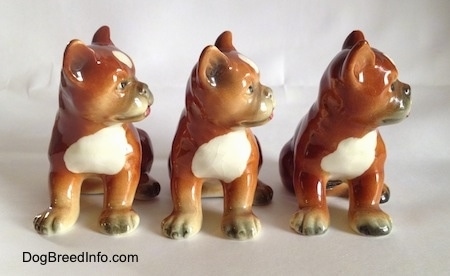Three brown with white and black Boxer puppy figurines. The figurines have detailed eyes.