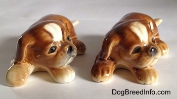 Two brown with white Boxer puppy figurines. The figurines have black circles for eyes.