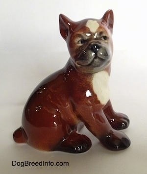 The right side of a brown with white and black Boxer puppy figurine. The figurine has a detailed face.