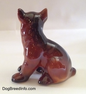 The left side of a brown with white and black Boxer puppy figurine. The figurine paws lack details.