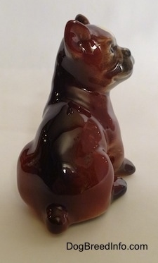 The back of a brown with white and black Boxer puppy figurine. The figurine is glossy.