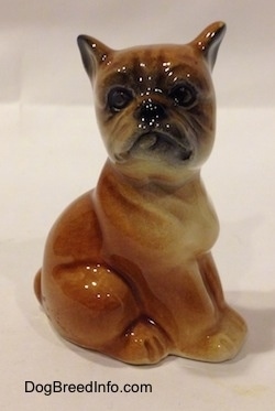 The right side of a brown with white Boxer puppy figurine that is in a sitting pose. The face of the figurine is very detailed.