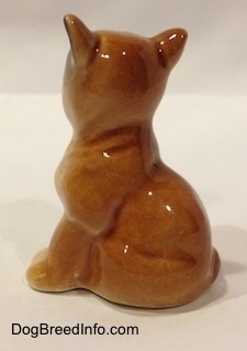 The left side of a brown with white Boxer puppy figurine that is in a sitting pose. The figurine is very glossy.