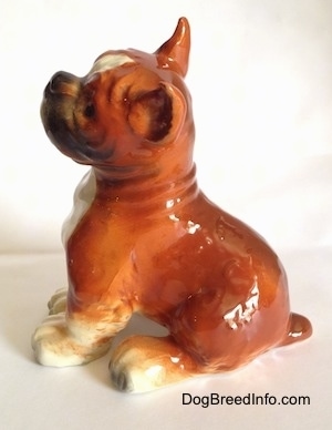 The left side of a porcelain brown with white and black Boxer dog figurine. The figurine has a detailed wrinkly neck.