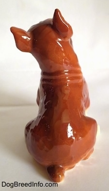 The back of a porcelain brown with white and black Boxer dog figurine. The figurine has a short tail.