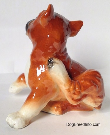 The left side of a brown with white and black Boxer dog figurine. The figurine has fine paw details.