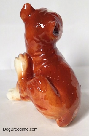 The back side of a brown with white and black Boxer dog figurine. The figurine is glossy.
