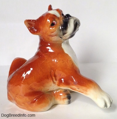 The right side of a brown with white and black Boxer dog figurine. The figurine has its paws attached to the side.