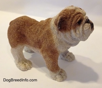 The right side of a brown and white ceramic mold of a Bulldog figurine. The paws of the figurine have fine details.