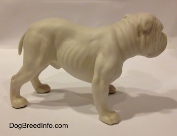 The right side of a white bisque porcelain Bulldog figurine. The figurine has a detailed body.