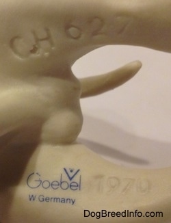 The underside of a white bisque porcelain Bulldog figurine. The figurine has numbers engraved on its legs. The numbers - 1970 - is on the left leg and the number/letter combination - CH627.