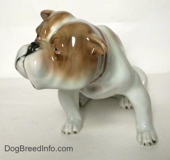 A white with brown Bulldog figurine in a sitting pose.
