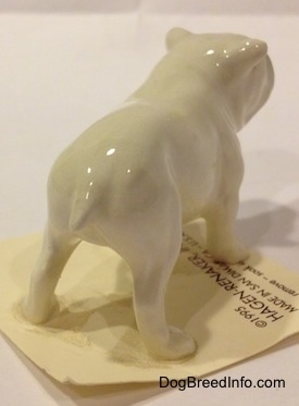 The back right side of a white miniature Bulldog figurine. The figurine has a short tail.