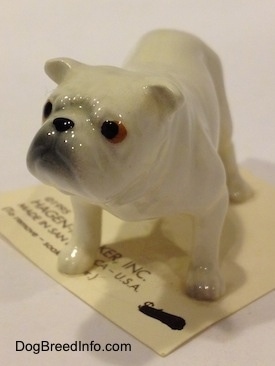 The front left side of a white miniature Bulldog figurine. The figurine has fine paw details.