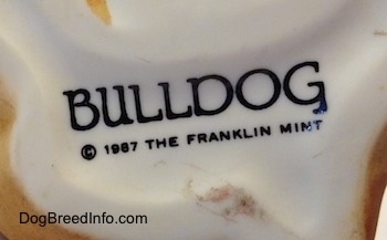 Close up - On the underside of a Bulldog puppy figurine there is a stamp that reads - BULLDOG © 1987 The Franklin Mint.