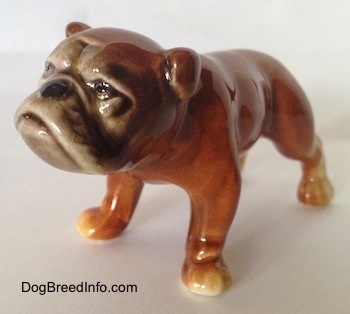 The front left side of a brown Bulldog figurine. The figurines paws have subtle details.