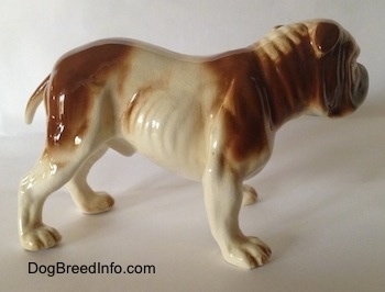 The right side of a brown and white with black Bulldog figurine. The figurine has detailed legs. It has a short tail that hangs down low.