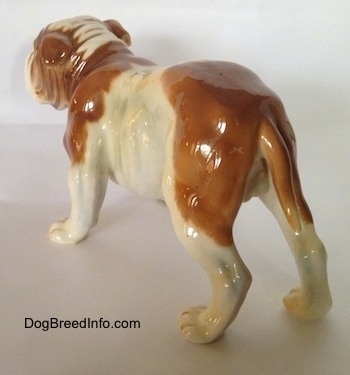 The back left side of a brown and white Bulldog figurine. The figurines ears are indistinguishable from its body.