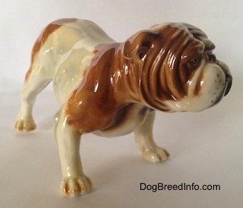 The front right side of a brown and white Bulldog figurine. The paws of the Bulldog figutine has fine details.