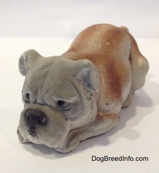 A cement mold paperweight made that is a brown with white English Bulldog figurine that is laying down. The figurine has great face details.