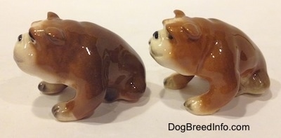 The left side of two brown with white miniature Bulldogs that are in a sitting pose. The figurines are glossy.