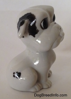 The right side of a white with black bone china Bulldog figurine. The black paint on the figurine is chipping away.