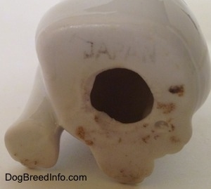A hole on the underside of a bone china Bulldog figurine that has the word - JAPAN - overtop of it.
