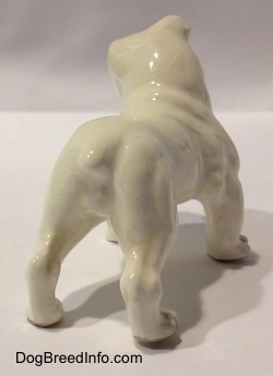 The back right side of a miniature white English Bulldog with a brown spot over the eye. The tail of the figurine is indistinguishable from the body.