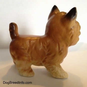 The right side of a tan with black Cairn Terrier figurine. The back of the figurines ears are black.