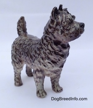 The front right side of a gray and white Cairn Terrier figurine. The figurine is very detailed.