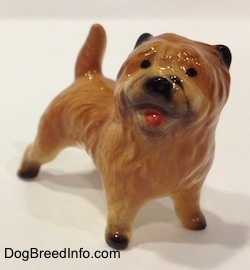 The front right side of a brown with black Cairn Terrier figurine. The figurine has black circles for eyes.