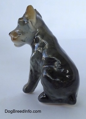 The back left side of a grey with black and tan Cane Corso Italiano puppy figurine. The figurine lacks fine detail.