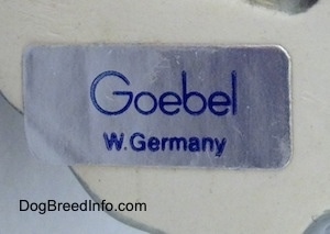 The underside of a Cane Corso Italiano puppy figurine that has a sticker on it. The sticker reads - Goebel W.Germany.