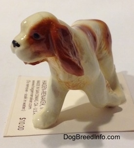 The front left side of a red and white Cavalier King Charles Spaniel figurine. The figurines mouth is painted to look like it is open.