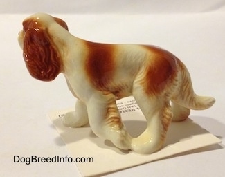 The left side of a red and white Cavalier King Charles Spaniel figurine. It is easy to tell the difference between the figurines ears and head.